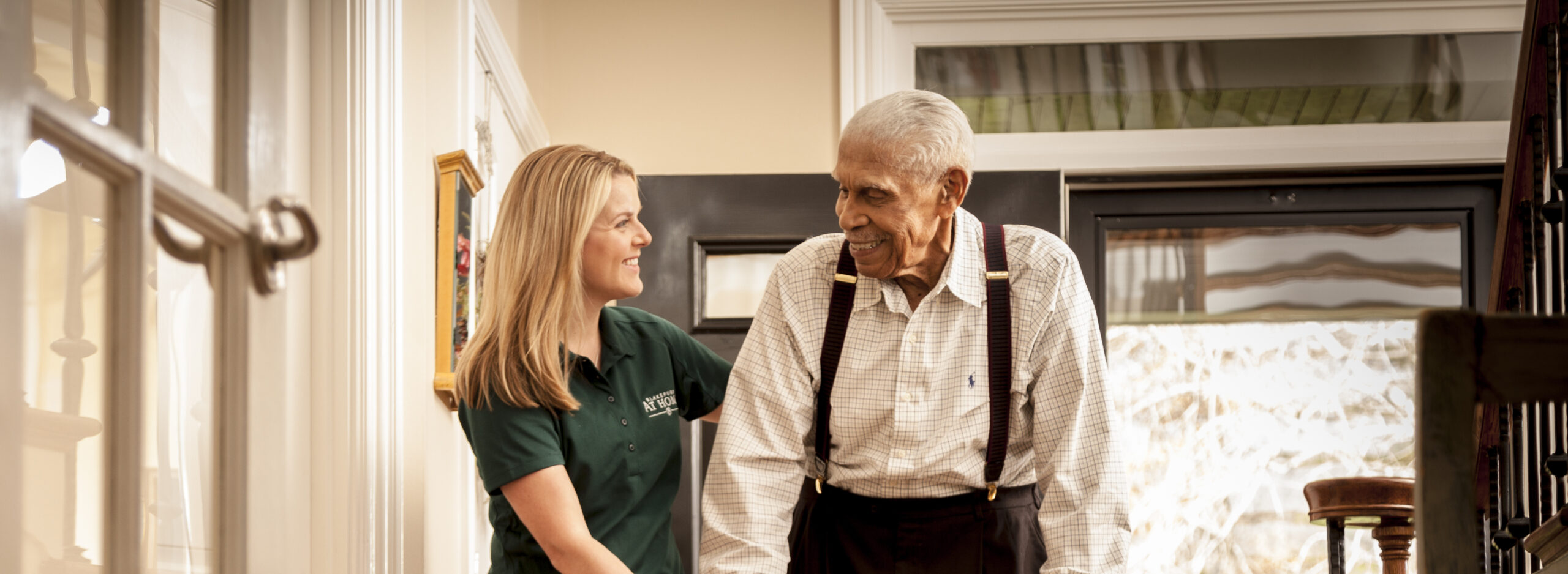 At home caregiver helping senior with mobility assistance.