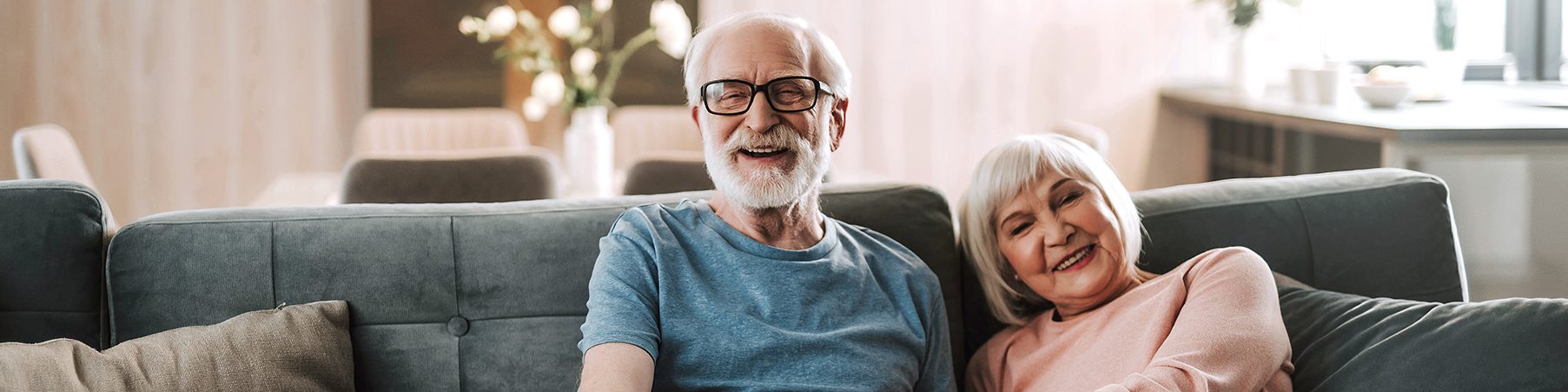 Happy elderly couple at home on couch