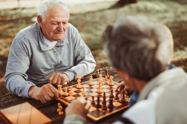 Senior men playing chess outside.