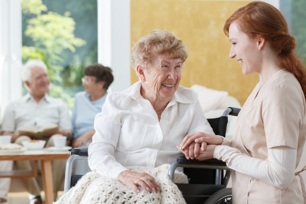 Senior woman smiling at care giver in assisted living community.